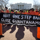 Protesters wearing orange jumpsuits depicting Guantanamo Bay detainees, hold a sign that reads "Not One Step Back Close Guantanamo" participate in a rally outside of the White House in Washington Monday, Jan. 11, 2016, calling for a close of the detention center at the U.S. base at Guantanamo Bay, Cuba.